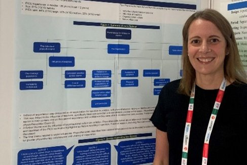 A woman stands in front of a research poster smiling at the camera