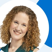 A woman smiling at the camera with curly ginger hair
