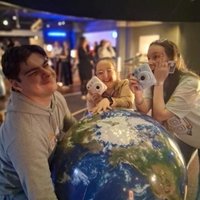 An image of three young people with cameras, around a large light up globe.