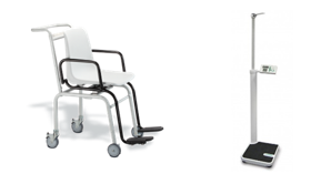 Two medical devices: a white chair with black armrests and footrests mounted on four wheels, and a digital scale with an attached height measuring rod and a small display screen for readings.