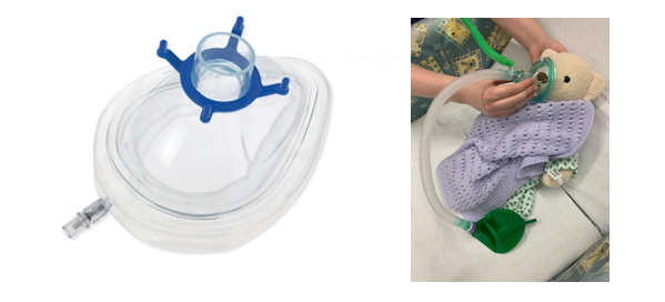 A clear plastic oxygen mask with a blue connector is shown on the left. On the right, a stuffed bear lies on a bed, covered with a purple blanket, while someone holds an oxygen mask over its face.
