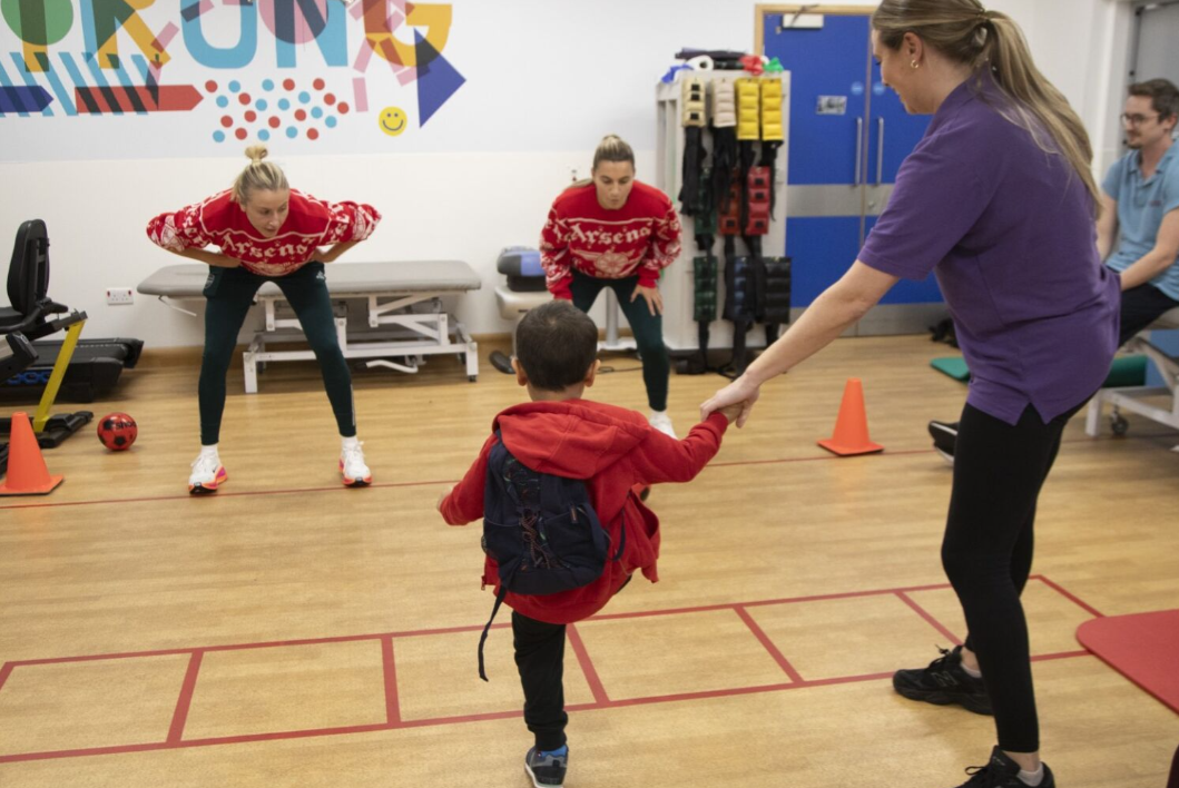 two arsenal womens players in goal with little boy taking penalty