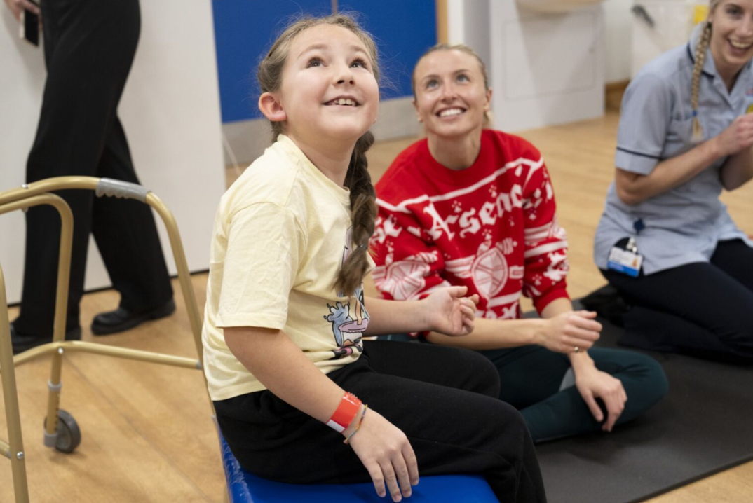 girl with plaits smiling and arsenal womens player leah in red jumper