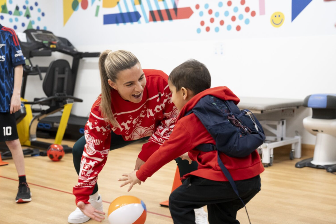 arsenal women player handing football to small child