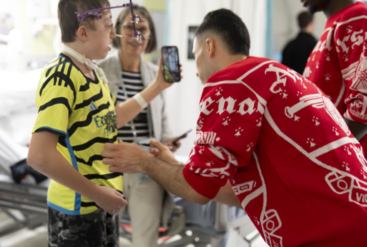 Arsenal player signing shirt of young boy on ward