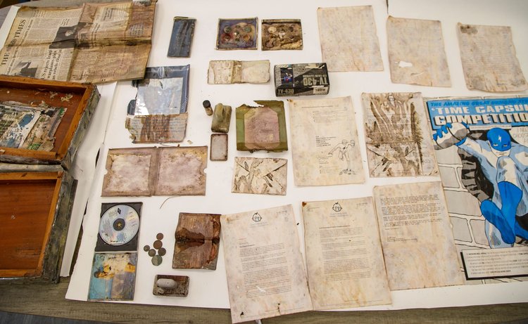A table with lots of items on it that were extracted from a time capsule and are damaged by water