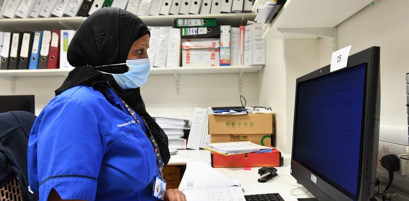 A member of GOSH staff at their computer, wearing a mask.