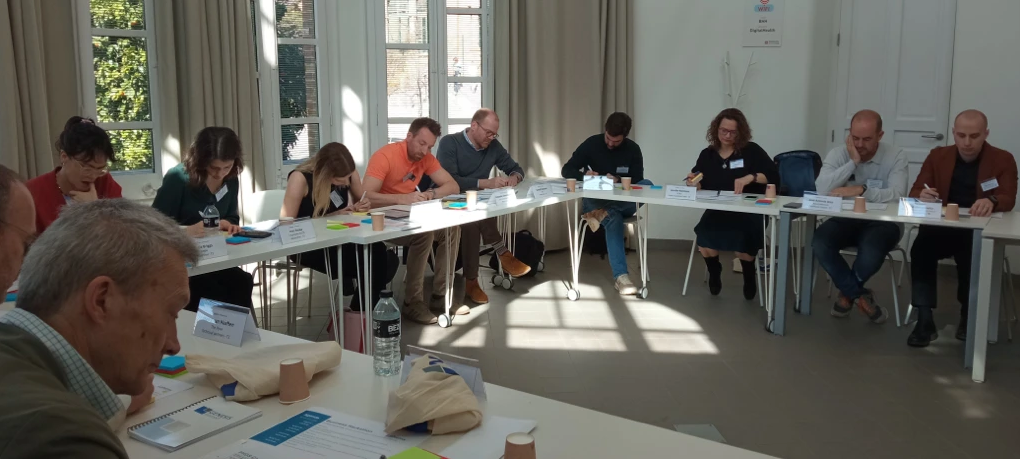 Group of adults sat around a large U-shaped table and writing on post-it notes.