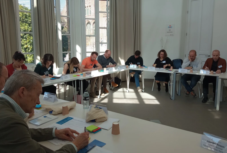 Group of adults sat around a large U-shaped table and writing on post-it notes.