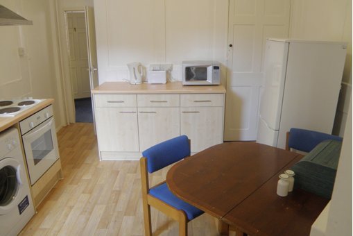 View of the kitchen facilities inside our staff accommodation  with washing machine, oven and hob, counter with kettle, toaster, and microwave, refrigerator, and small table and chairs, ke