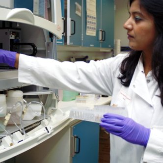 Woman in white lab coat placing samples in a sample rack in the laboratory
