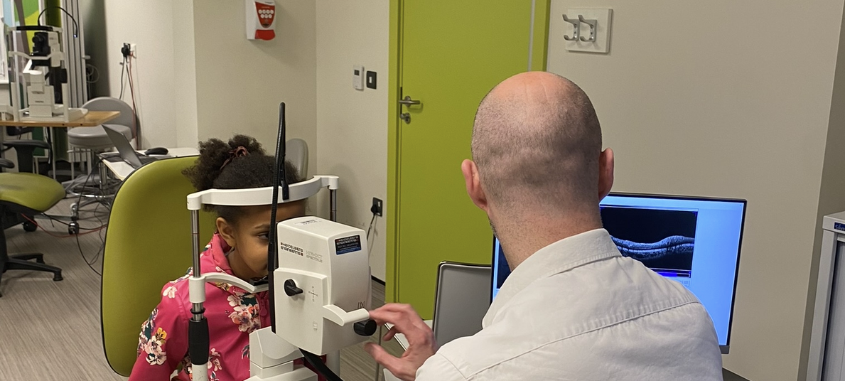 A clinician is checking a child's eyes using a imaging device