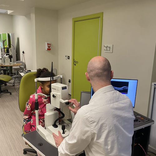 A clinician is checking a child's eyes using a imaging device