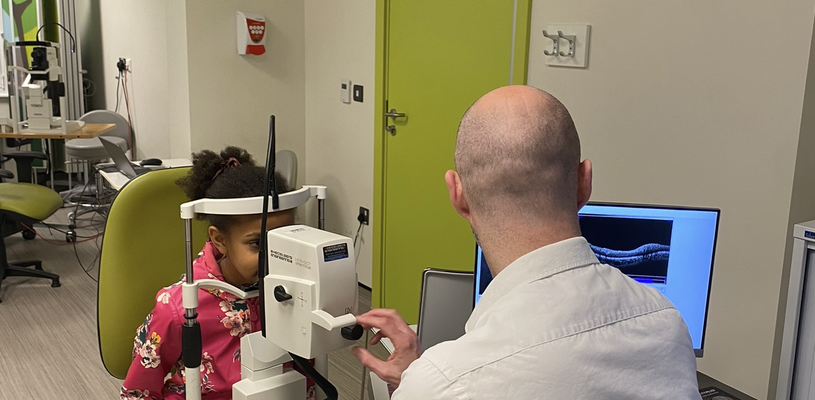 A clinician is checking a child's eyes using a imaging device