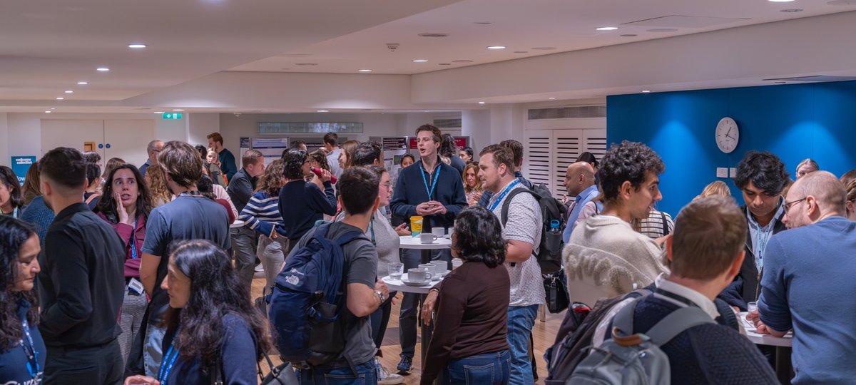 A Crowd of people standing and talking in a busy room