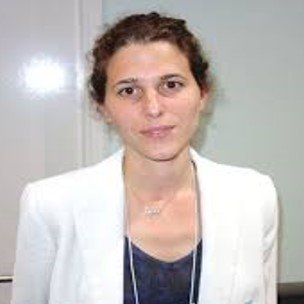 A staff member smiling, wearing a white blazer